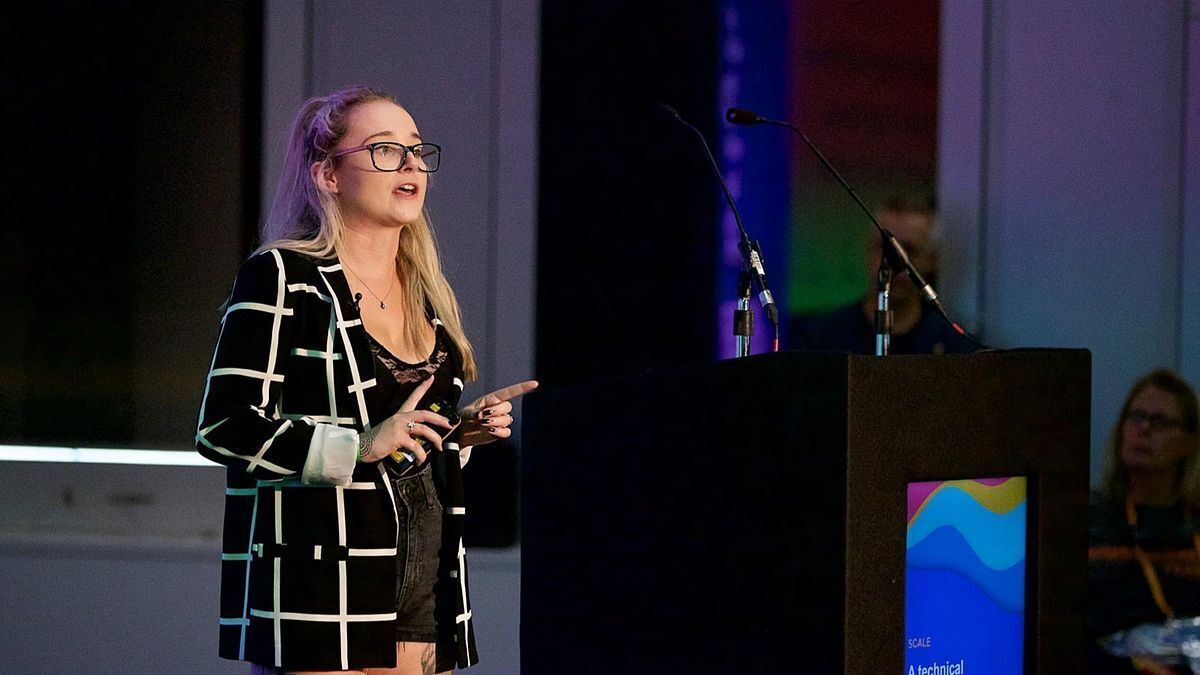 Sophie Brannon speaking at a lectern, gesturing to the audience